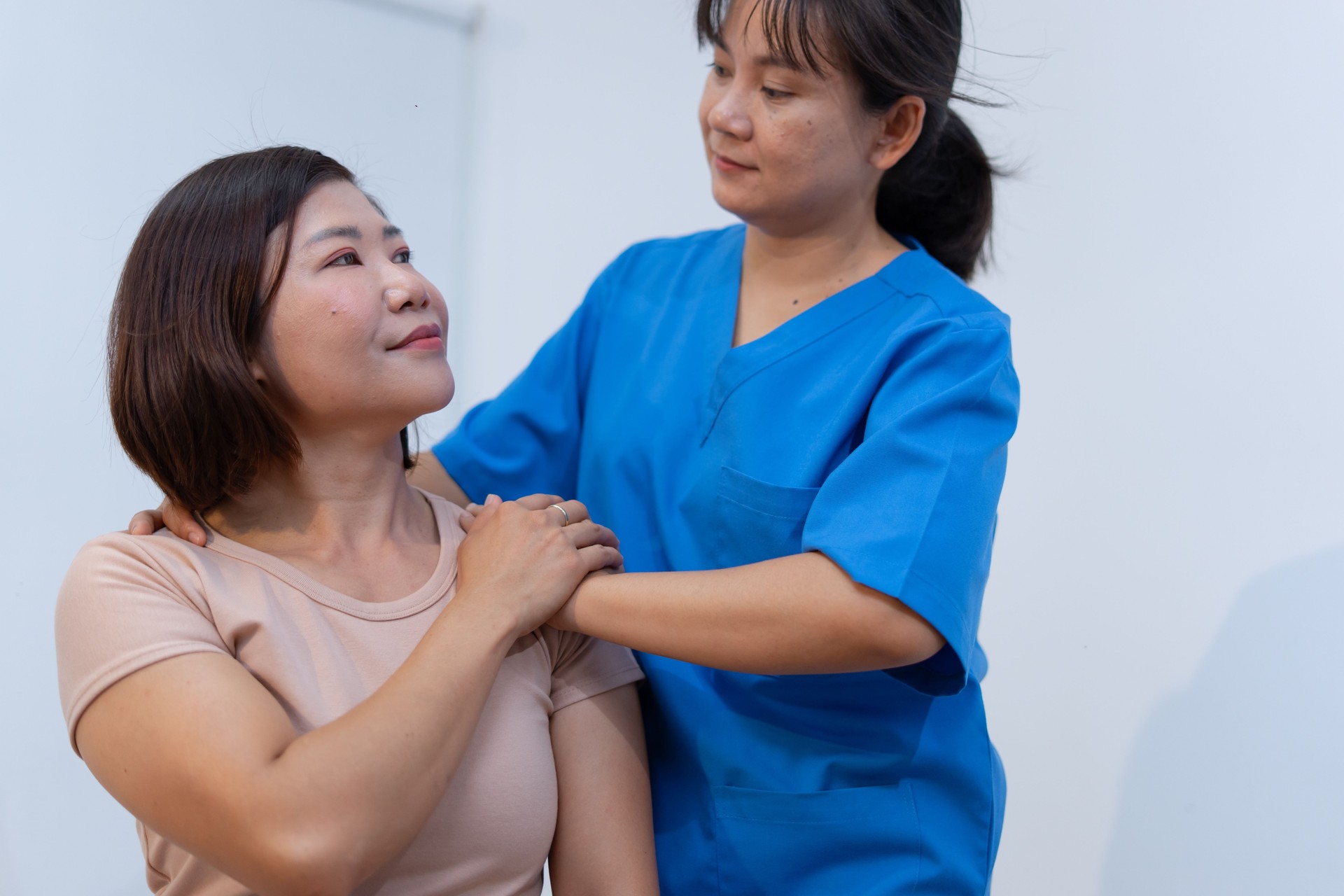 Healthcare professional in blue scrubs assists patient with care