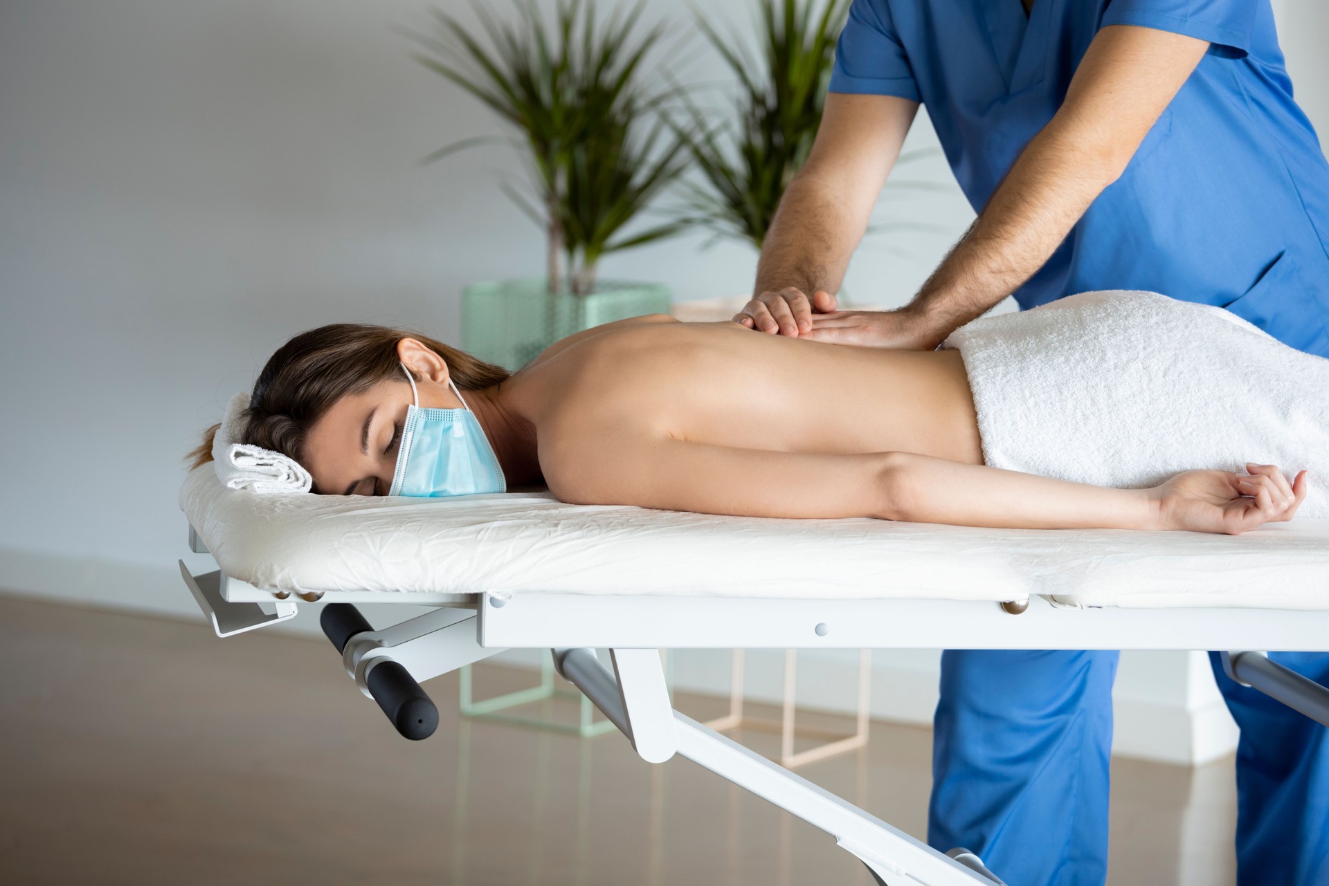 Young woman receiving a physio-therapeutic shoulder massage during Coronavirus Pandemic.